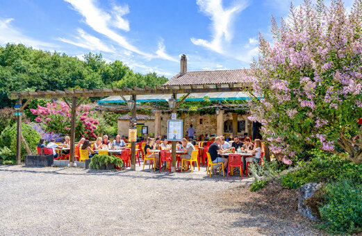 Terrasse de restaurant extérieure avec convives et pergola au camping CAPFUN Moulinal à BIRON (24).
