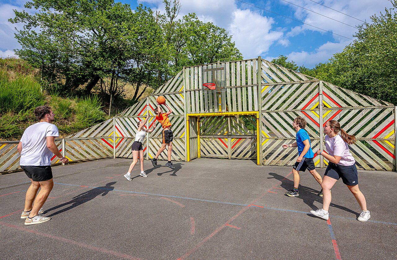 Multisportterrein met jongeren die basketballen op camping VAGUES OCEANES Moulin de Cadillac in Noyal-Muzillac (56).