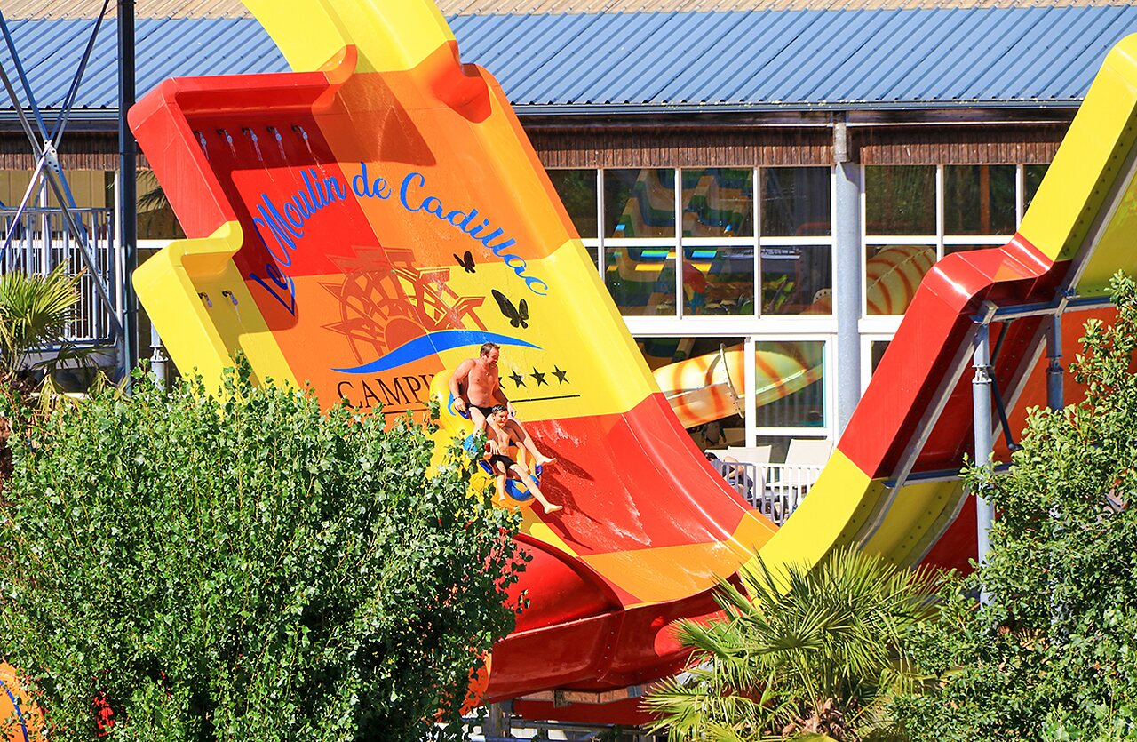 Reusachtige waterglijbaan met vader en kind op camping VAGUES OCEANES Moulin de Cadillac.