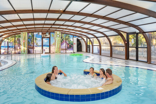 Piscine couverte avec jacuzzi et famille profitant au camping VAGUES OCEANES Moustoir à Carnac (56).