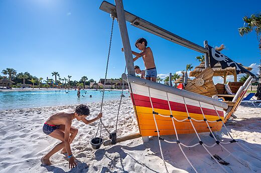 Piratenboot-Spielplatz und Lagunenpool auf dem Campingplatz CAPFUN La Nautique in Narbonne.