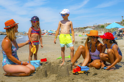 Familie met kinderen op het zandstrand op camping CAPFUN Or in La Grande Motte (34).