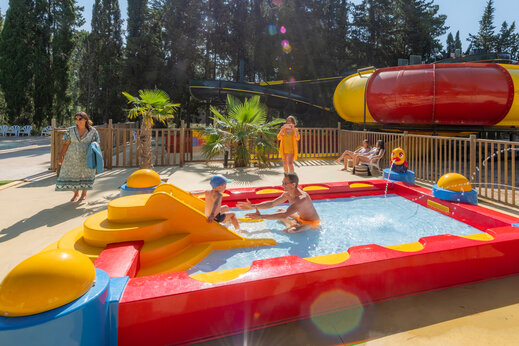 Kleurrijk peuterbad met glijbaan en waterspelen op camping CAPFUN Or in La Grande Motte (34).