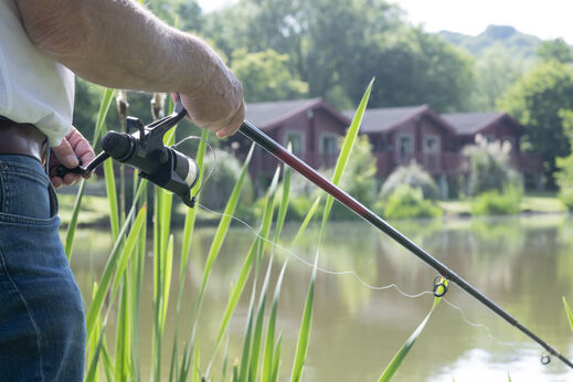 Angler mit Angelrute und Rolle am See auf dem Campingplatz CAPFUN UK Otter Falls in Upottery Nr Honiton.