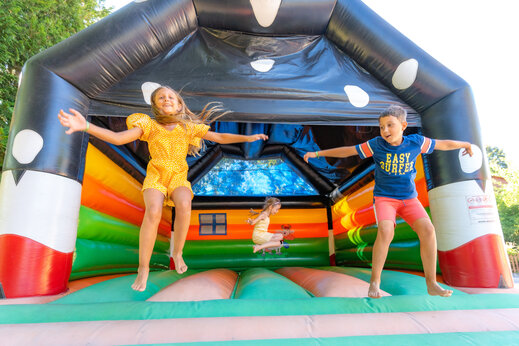 Kinder springen fröhlich auf einer bunten Hüpfburg auf dem Campingplatz CAPFUN Oursière in Villard de Lans (38).