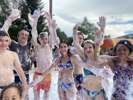 Lachende Kinder und Jugendliche genießen eine Schaumparty auf dem Campingplatz CAPFUN Oursière in Villard de Lans (38).