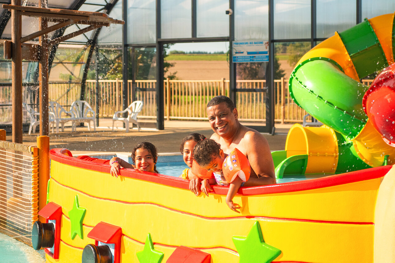 L�chelnde Familie in Wasserspielstruktur mit Rutsche auf dem Campingplatz CAPFUN Pachy in FOSSES LA VILLE.