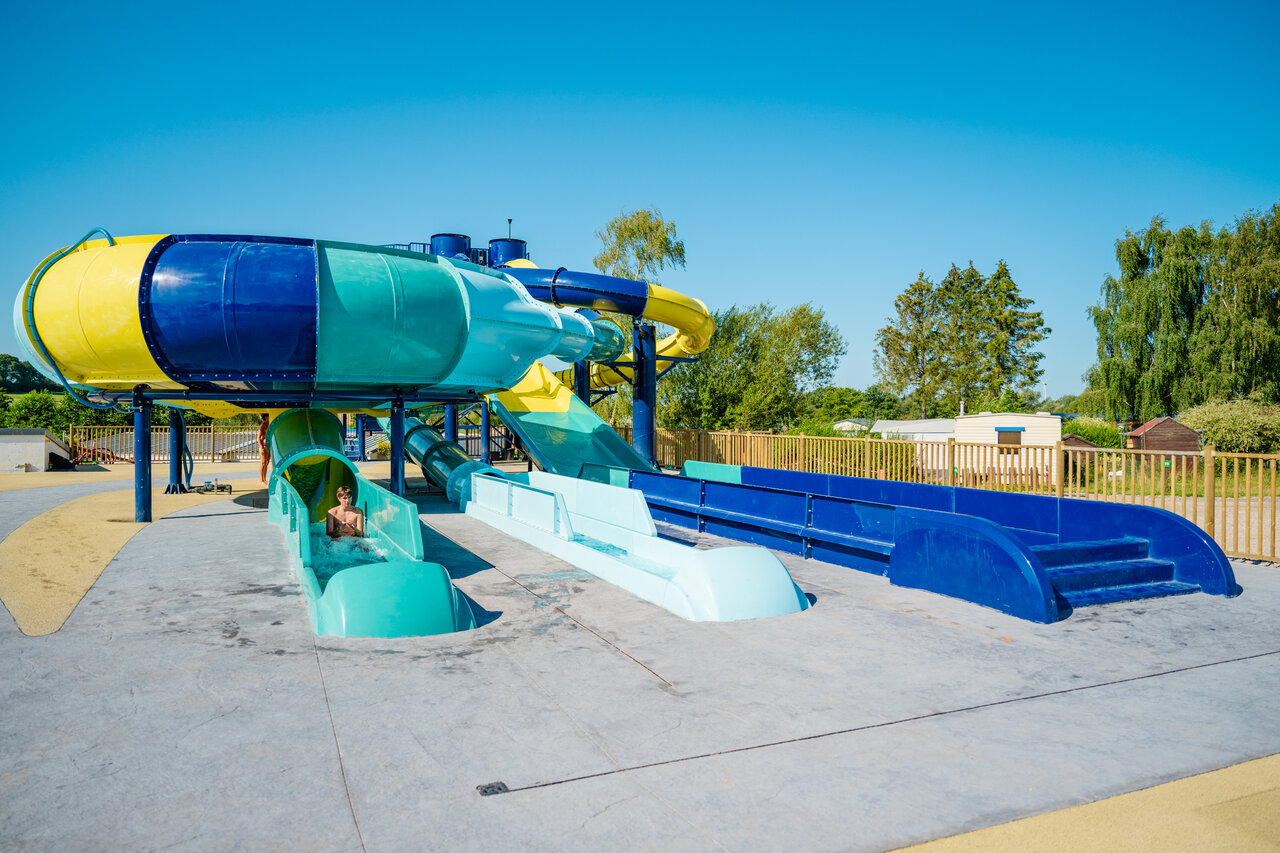 Bunte Wasserrutschen und Kind beim Spa� auf dem Campingplatz CAPFUN Pachy in FOSSES LA VILLE.