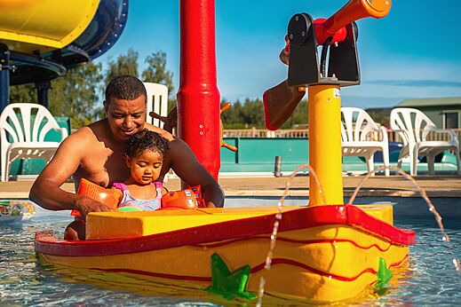 Kind und Vater spielen im Wasserspielbereich auf Camping CAPFUN Pachy in FOSSES LA VILLE.