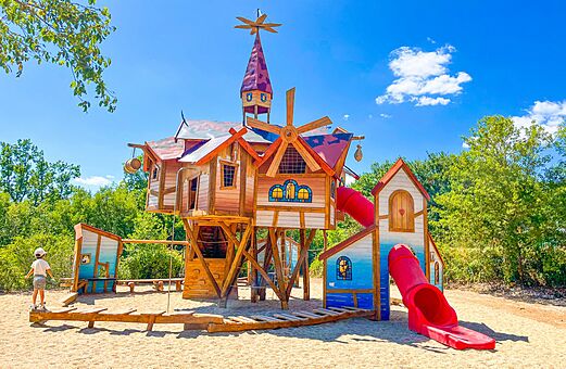 Gro�er Holzspielplatz mit roter Rutsche f�r Kinder auf dem Campingplatz VAGUES OCEANES Paille Basse in Souillac (46).