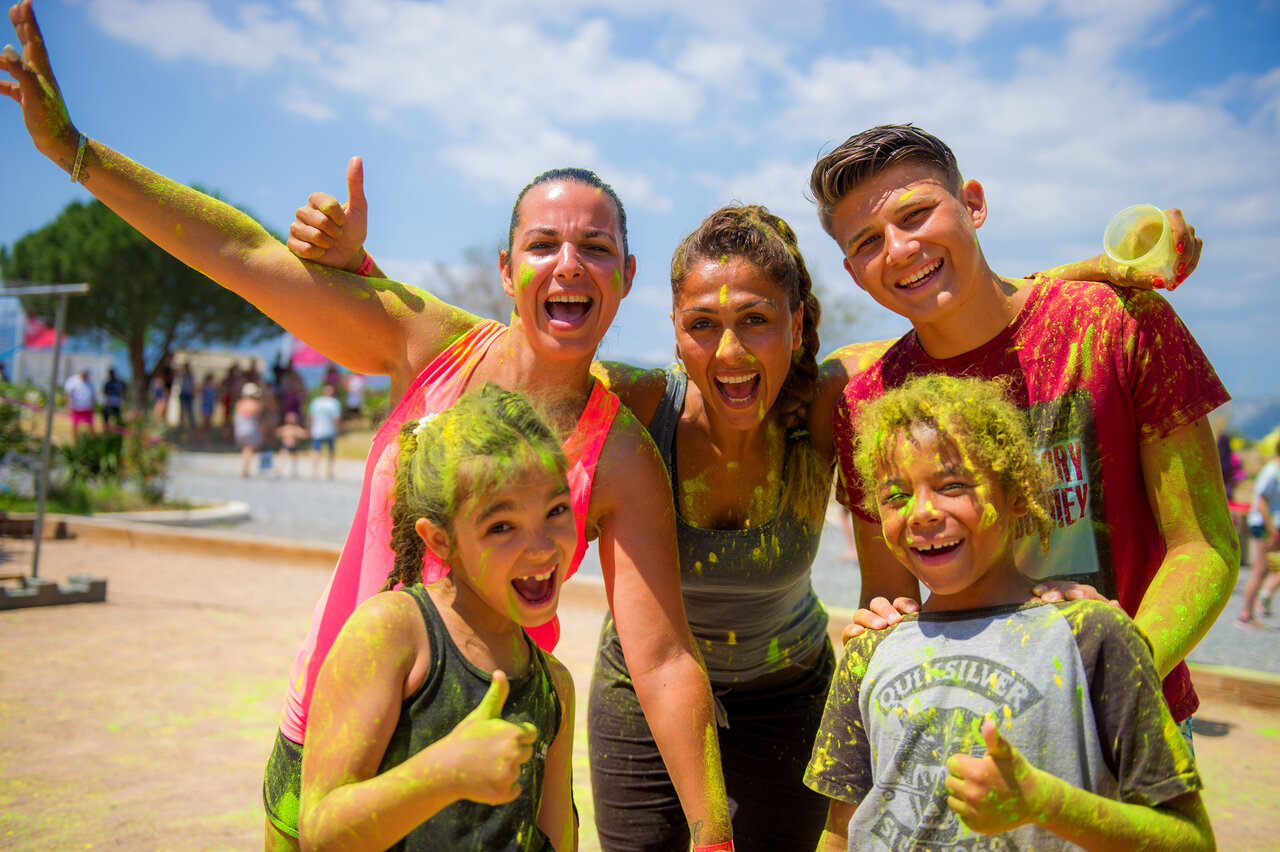 Smiling family and friends with color powder, at CAPFUN Palombi�re campsite in Sarlat (24).