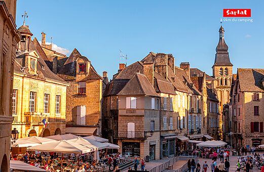 Lebhafter Platz in Sarlat-la-Canéda mit Straßencafés und mittelalterlicher Architektur.