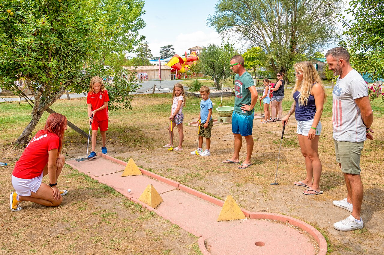 Family and children playing mini-golf with animator at CAPFUN Paradis de Bazas campsite in BAZAS (33).