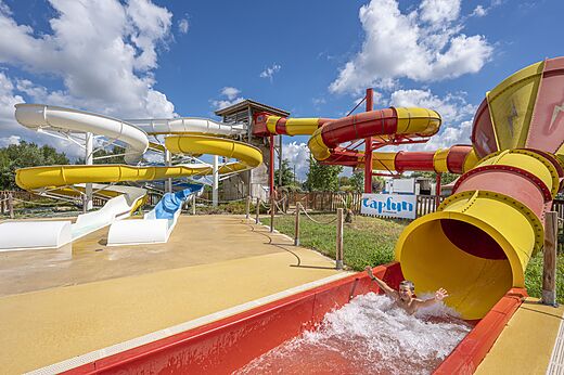 Bunte Wasserrutschen und Kind rutscht auf dem Campingplatz CAPFUN Paradis de Bazas in BAZAS (33).