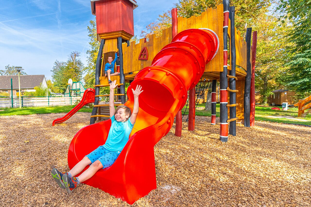 L�chelndes Kind auf roter Rutsche Spielplatz auf Camping CAPFUN Parc de Paris in Villevaud� (77).