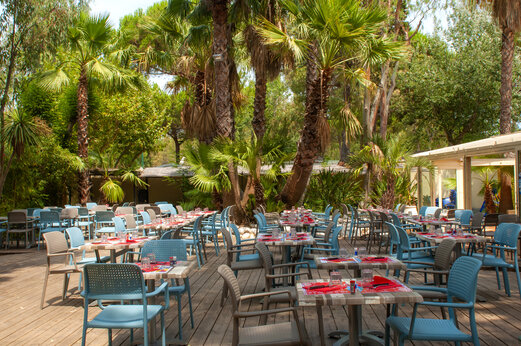 Außenrestaurant, Tische und Stühle unter Palmen, Camping CAPFUN Parc et Plage.