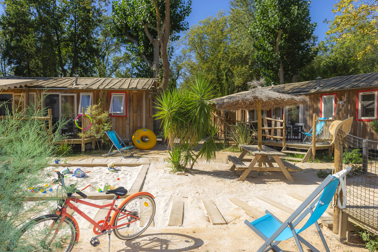 Wooden mobile homes, sandbox, bicycle at CAPFUN Paris Roussillon campsite in ARGELES SUR MER.
