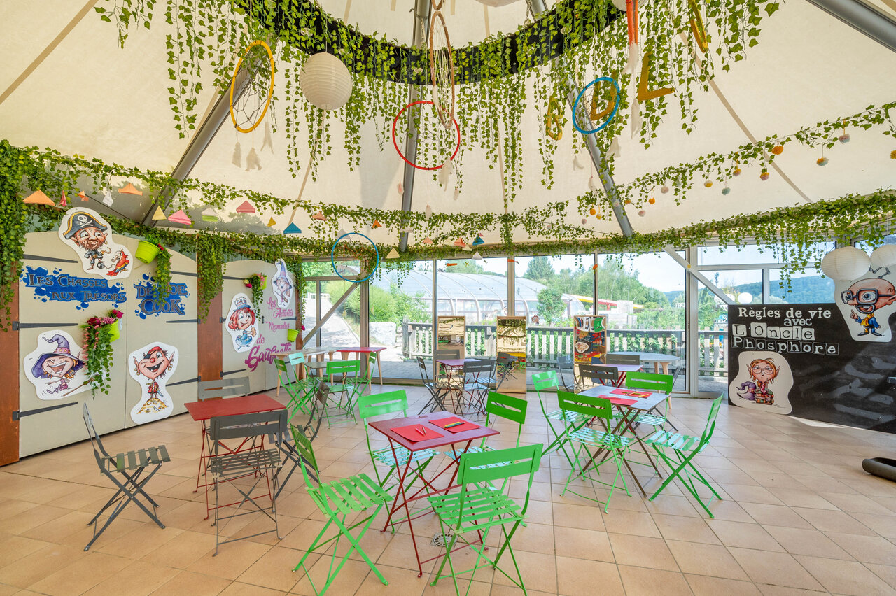 Colorful children's animation area with tables and decorations at CAPFUN Pergola campsite in Marigny (39).