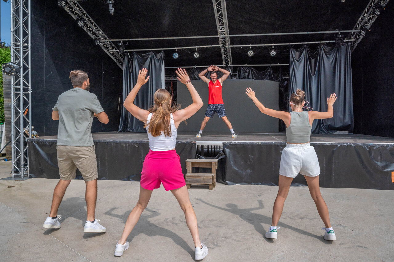 Animator and campers exercising on stage at CAPFUN Pergola campsite in Marigny (39).