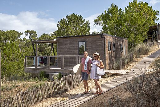 Holz-Mobilheim, Paar auf Sandweg auf dem Campingplatz CLICOCHIC Petit Bec in St Hilaire de Riez.