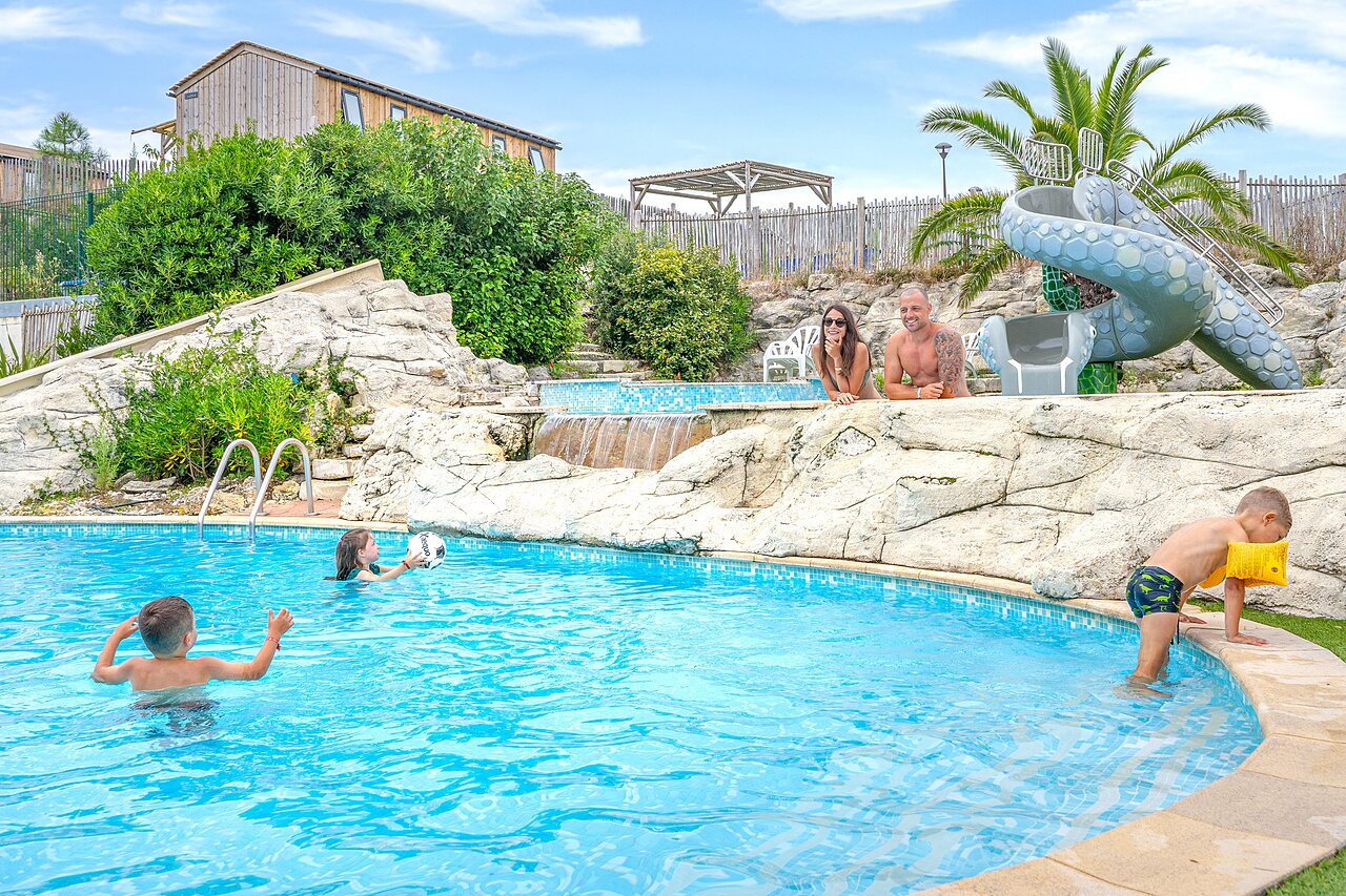Family enjoying the swimming pool with slide and waterfalls at camping CLICOCHIC Petit Nice in PYLA SUR MER (33).