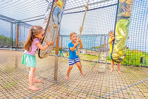 Kinder vergnügen sich im Netzspielplatz von Camping CLICOCHIC Petit Nice.