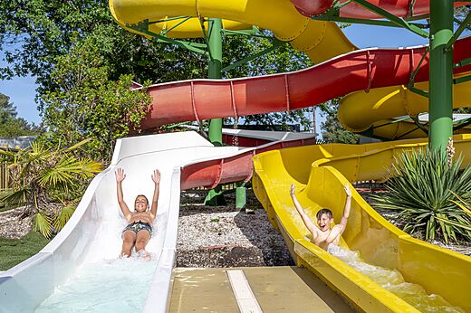 Fröhliche Kinder auf bunten Wasserrutschen am Campingplatz CAPFUN Pinèda in CAZAUX (33).