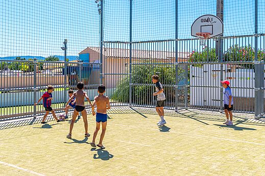 Kinder spielen Fußball und Basketball auf Multisportplatz auf Camping CAPFUN La Pinède de Grimaud.