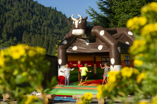 Kinder spielen auf aufblasbarem Kuh-Spielplatz auf Camping CAPFUN Plan du Fernuy.