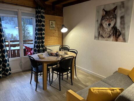 Innenansicht Mobilheim mit Esstisch und verschneitem Bergblick auf Camping CAPFUN Plan du Fernuy in LA CLUSAZ (74).