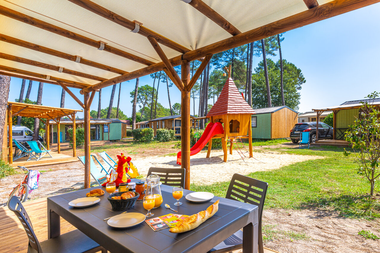 Breakfast on Mobil-home terrace with children's playground at CAPFUN Pomme de Pin campsite in Saubion (40).