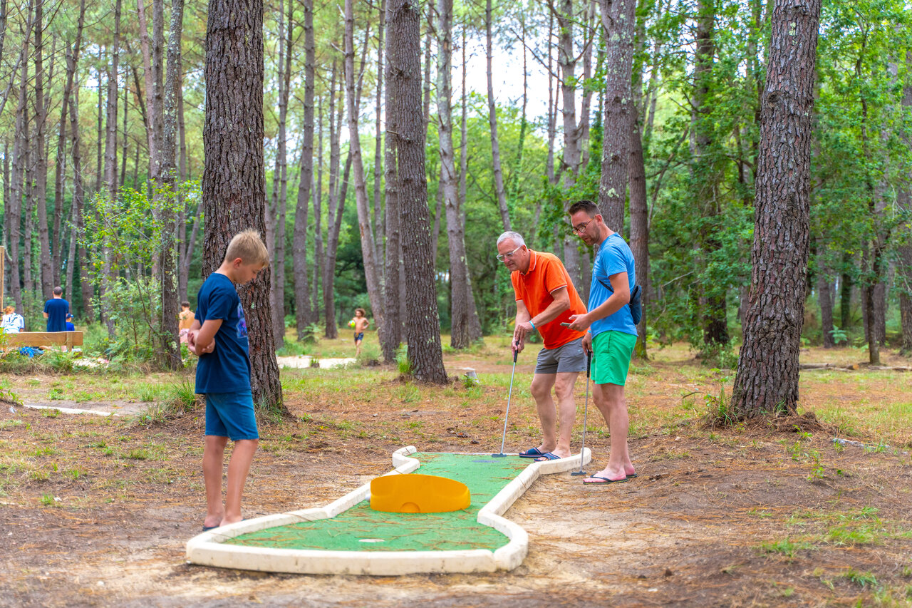 Family playing mini-golf in forest, CAPFUN Pomme de Pin campsite in Saubion (40).