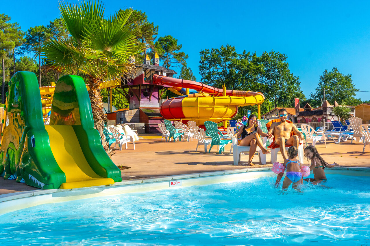 Colorful water slides and family pool with children at CAPFUN Pomme de Pin campsite in Saubion (40).