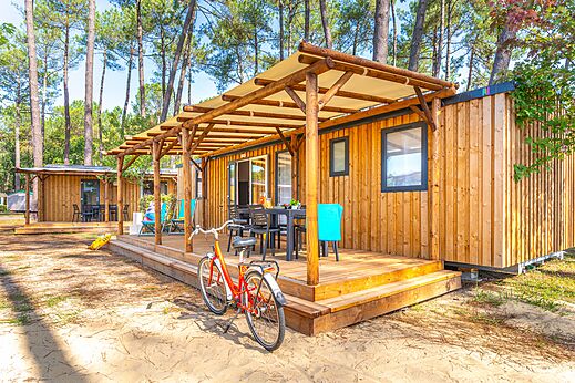 Modernes Mobilheim mit überdachter Terrasse und Fahrrad auf dem Campingplatz CAPFUN Pomme de Pin in Saubion (40).