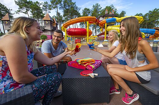 Freunde mit Cocktails nahe Wasserrutschen auf Camping CAPFUN Pomme de Pin Saubion (40).