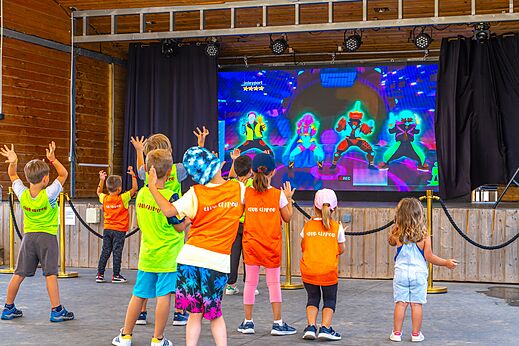 Kinder nehmen an interaktiver Animation auf Großbildschirm teil auf dem Campingplatz CAPFUN Pomme de Pin in Saubion (40).