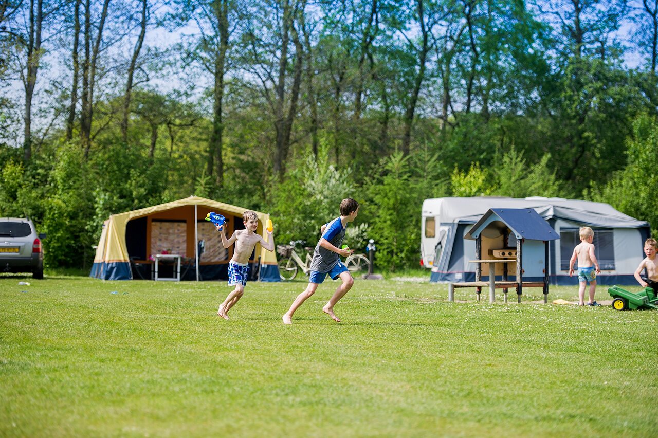 Kinder spielen mit Wasserpistolen auf einem Campingplatz bei CAPFUN Ponderosa in Ulicoten.