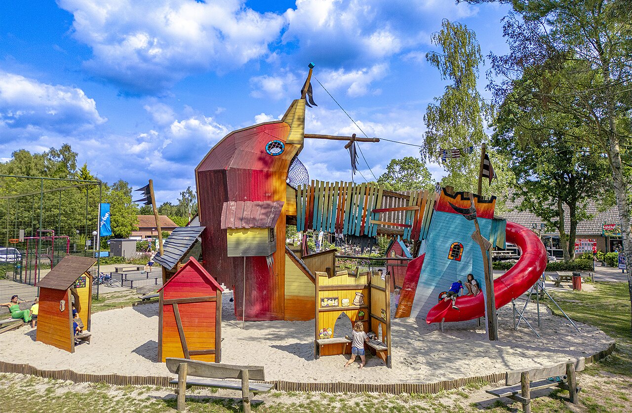 Thematischer Spielplatz mit Piratenschiff und Rutsche auf dem Campingplatz CAPFUN Ponderosa in Ulicoten