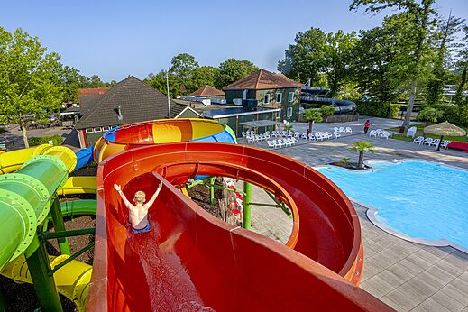 Bunte Riesenrutsche und Außenpool auf dem Campingplatz CAPFUN Ponderosa in Ulicoten.