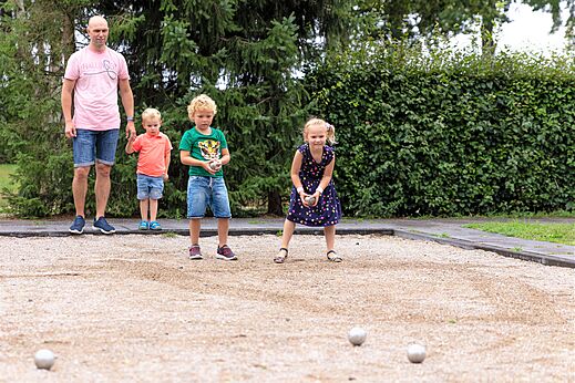 Familie spielt Boule auf dem Platz des Campingplatzes CAPFUN Ponderosa in Ulicoten.