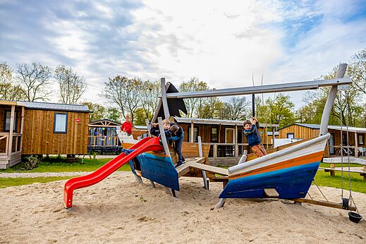 Spielplatz Boot, Rutsche und Kinder auf dem Campingplatz CAPFUN Ponderosa in Ulicoten.