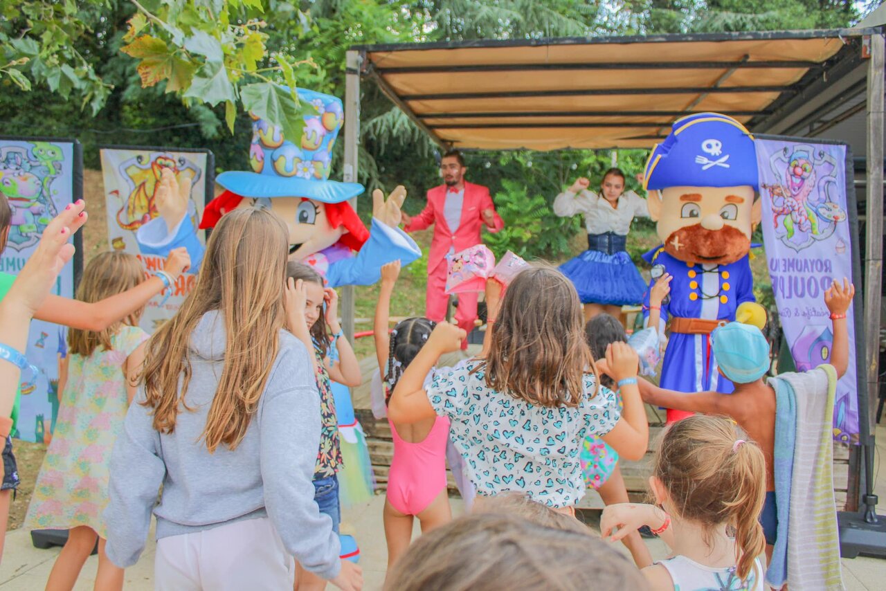 Kinderen dansen met mascottes en animators op podium op camping CAPFUN Les Portes du Beaujolais in Anse (69).
