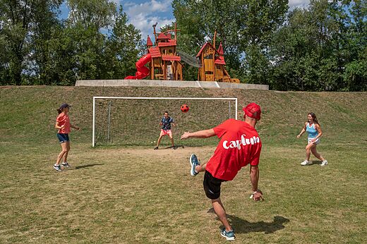 Familie spielt Fußball auf Sportplatz mit Spielplatz auf Camping CAPFUN Les Portes du Beaujolais in Anse (69).