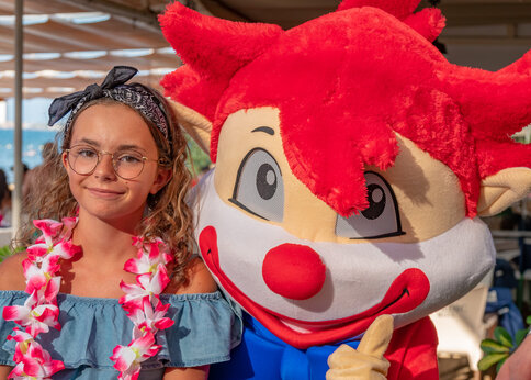 Campingmaskottchen und lächelndes Mädchen auf dem Campingplatz CAPFUN Serra de Prades.