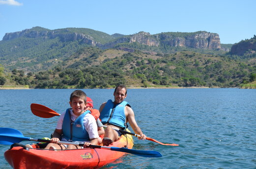 Vater und Kind im Kajak auf dem See auf dem Campingplatz CAPFUN Serra de Prades in Vilanova de Prades.