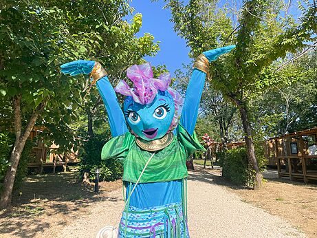 Lachende campingmascotte met opgeheven armen voor animatie op camping VAGUES OCEANES Pr�s de la Fontaine � Gouaix (77).