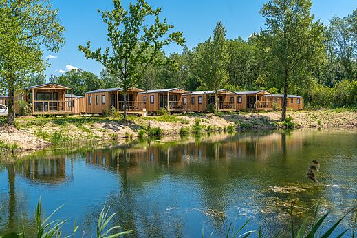 Houten stacaravans aan een vijver, op camping VAGUES OCEANES Pr�s de la Fontaine � Gouaix (77).