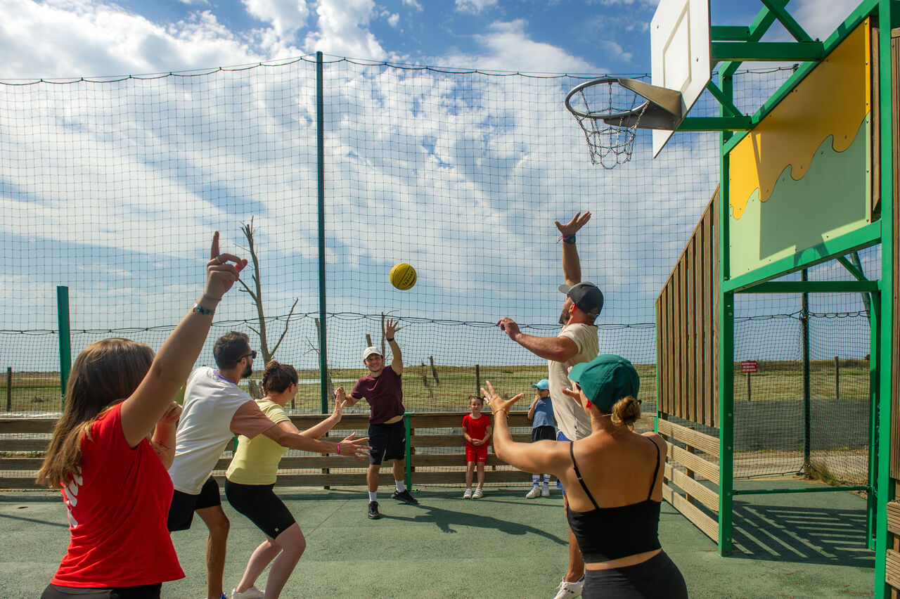 Familie spielt Basketball auf Multisportplatz auf dem Campingplatz CAPFUN Prises in La TRANCHE SUR MER (85).