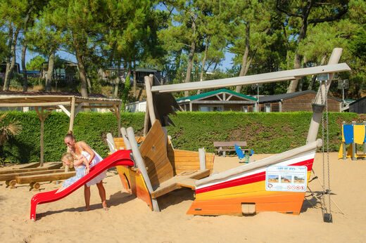 Spielplatz mit Holzboot, Rutsche und Kindern auf dem Campingplatz CAPFUN Prises in La TRANCHE SUR MER (85).