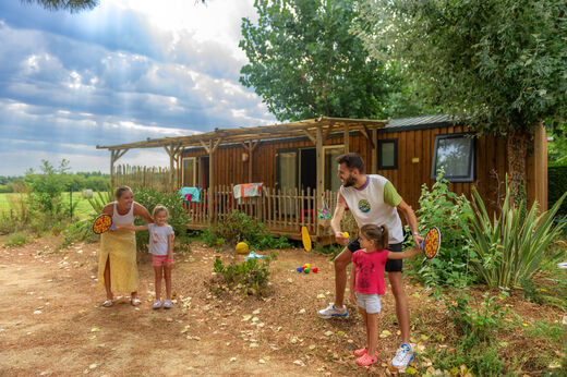 Familie spielt vor einem Mobil-home mit Terrasse auf dem Campingplatz CAPFUN Prises in La TRANCHE SUR MER (85).